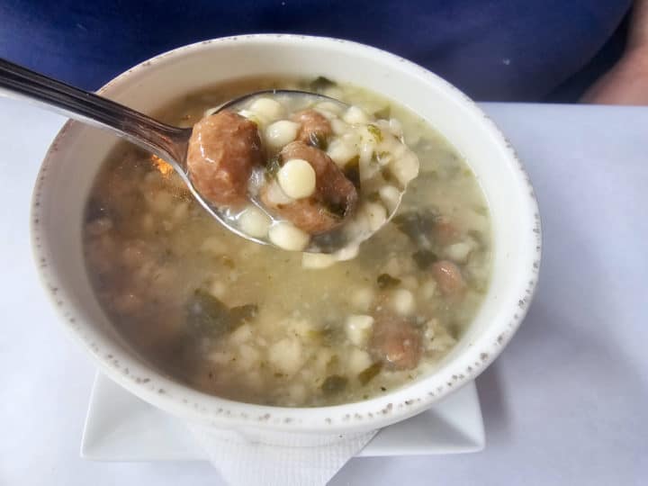 Italian Wedding Soup on a spoon above a white bowl