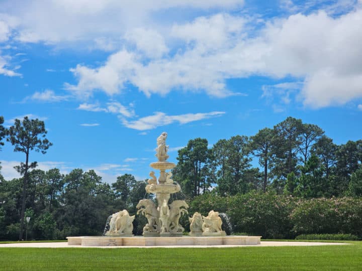 Neptune's Fountain with trees behind it and clouds in the sky