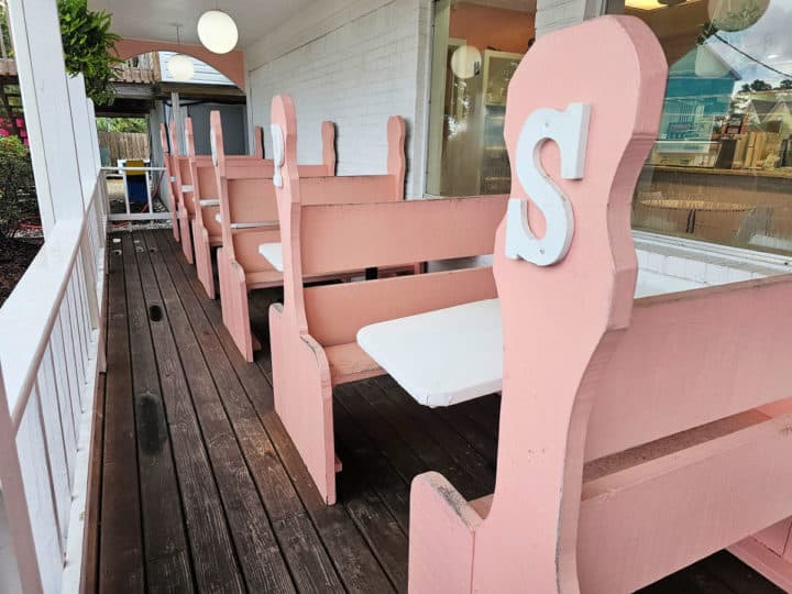 pink benches with white tables outside of Scoops Ice Cream