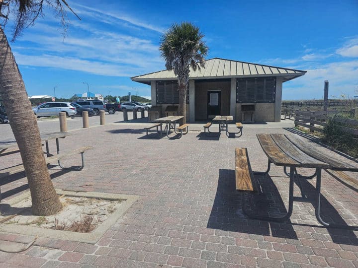 picnic tables and palm trees next to a restroom pavilion at the beach