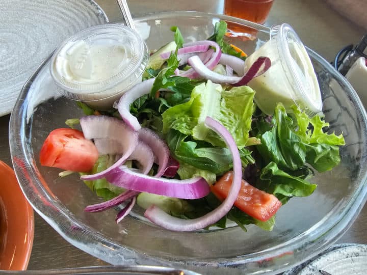 Salad in a glass bowl with ranch dressing cups