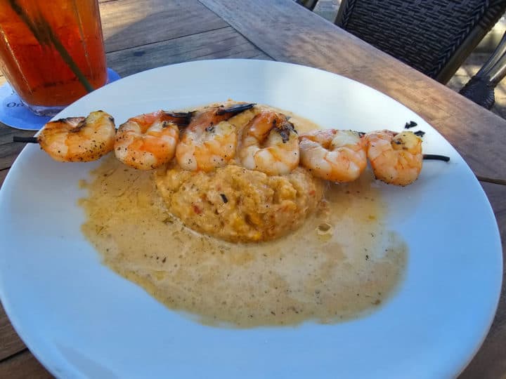 Shrimp and Grits on a white plate with tea in the background