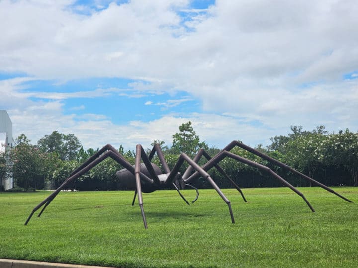 Metal spider sculpture in a grassy field
