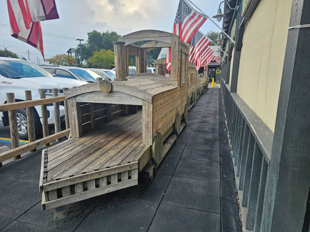 Wooden train play structure with American flags flying above it at Lambert's Cafe Foley