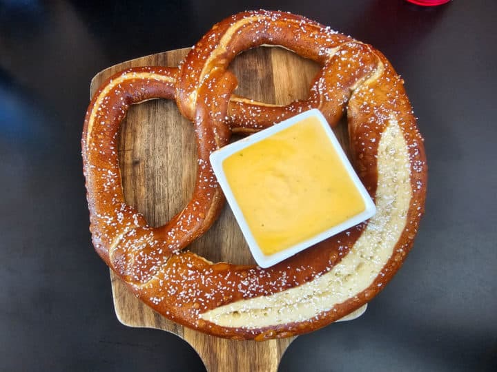 Bavarian pretzel on a board with a bowl of cheese dip