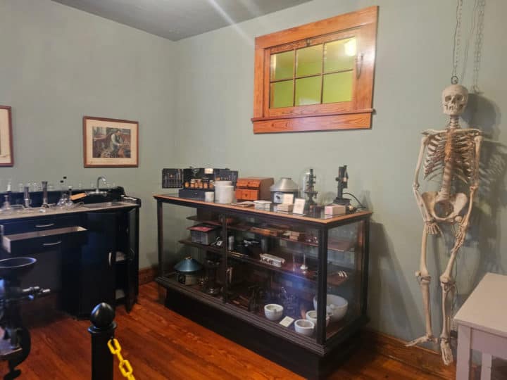 Skeleton hanging next to pharmacy cabinets 