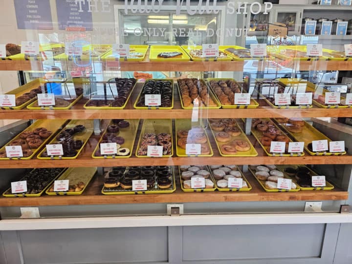 doughnuts on yellow trays behind a plastic screen