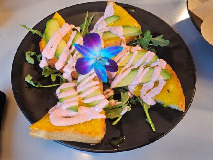 Egg covered toast points with avocado on a dark plate