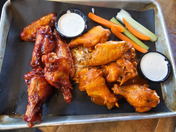 chicken wings on a silver platter with celery and carrot sticks