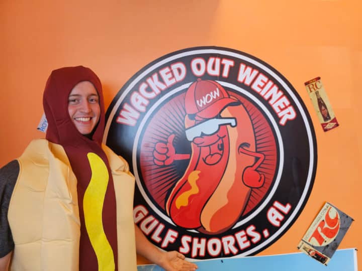 Nathan dressed in a hot dog costume next to the Wacked out Weiner sign