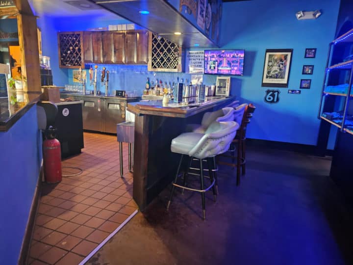 bar seating with padded stools near a blue wall and drink dispensers. 