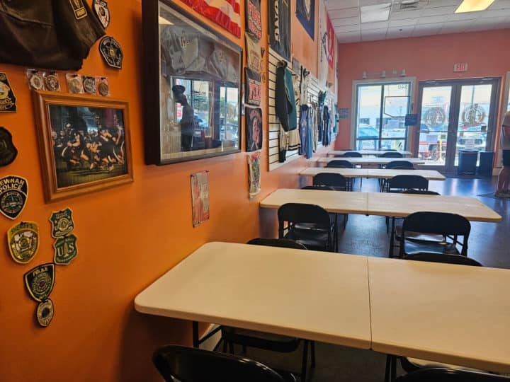 indoor tables and folding chairs next to an orange wall with photos on it