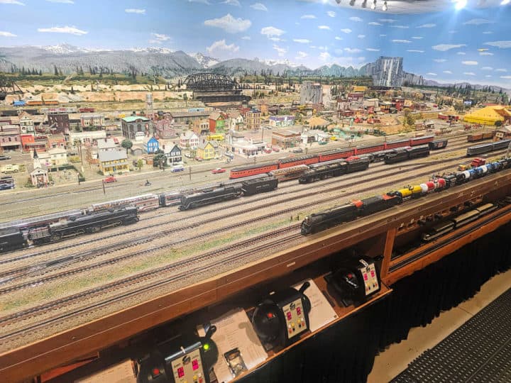 Model train exhibit with multiple train tracks and a city