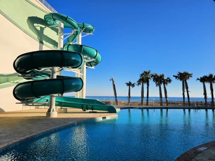 waterslide circling into a tropical pool with palm trees in the background and the Gulf of Mexico 
