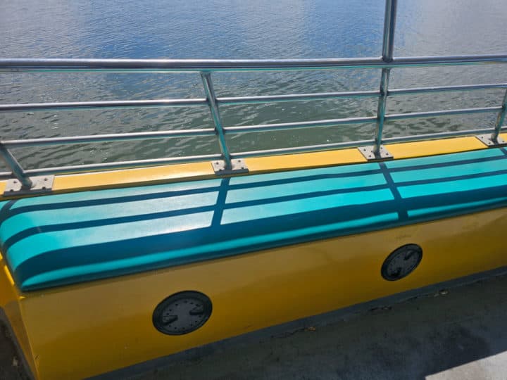 outdoor seating with a turquoise padded bench and view of the water