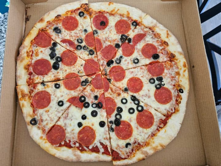 pepperoni and black olive pizza in a delivery box