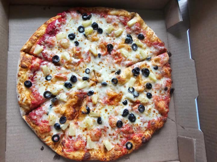 pineapple black olive pizza in a cardboard box