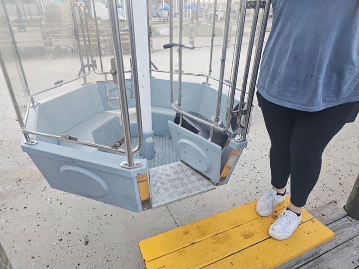 Person standing next to the entrance to the Wharf Ferris Wheel pod