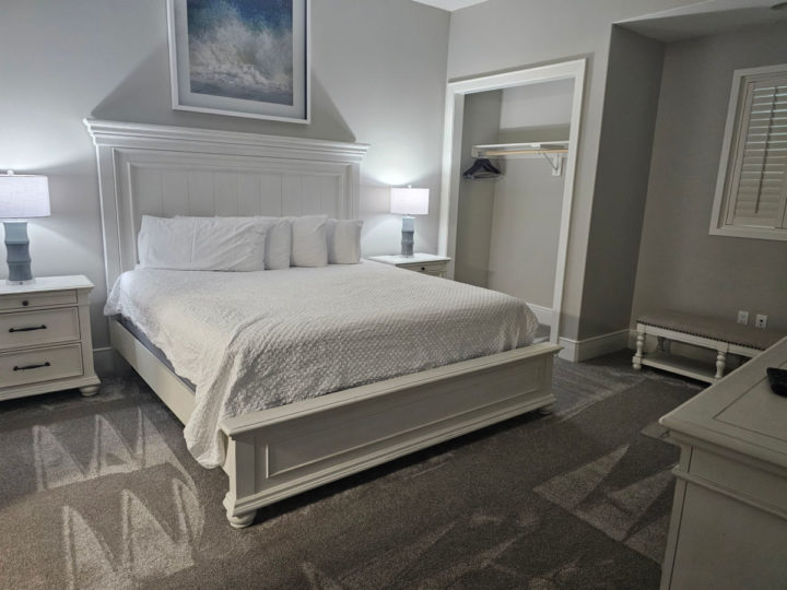 bedroom with bed, white comforter nightstand, dresser, and open closet