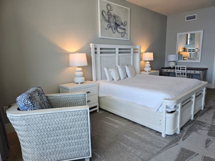 master bedroom with white comforter on a king size bed, chair, and desk in the corner