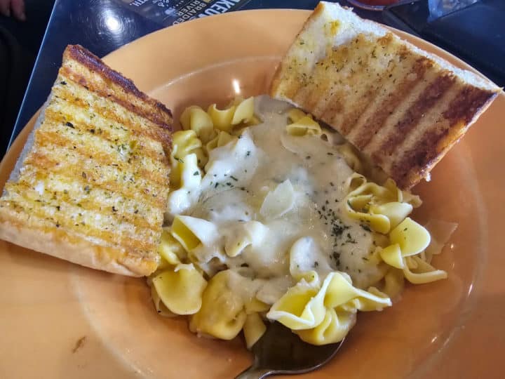 pear and goat cheese Sachetti Pasta with garlic bread on an orange plate