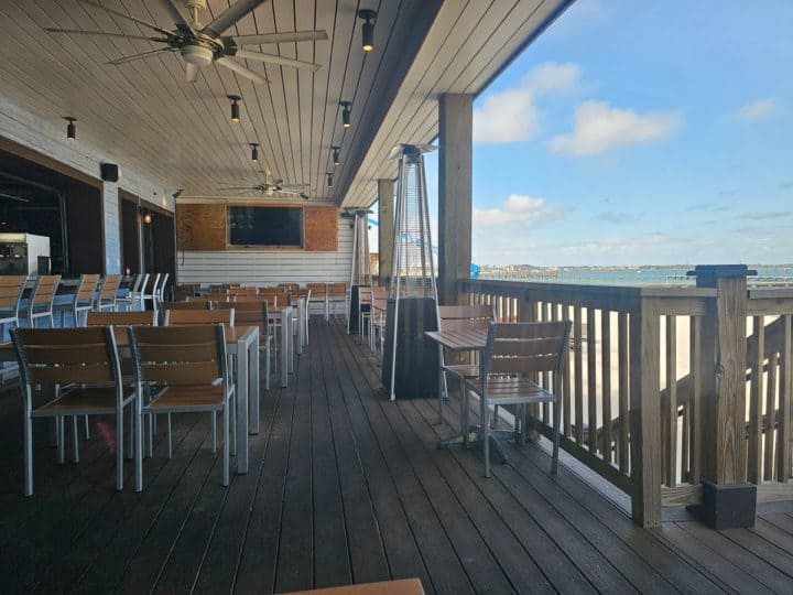 covered deck seating with views of the water and a tv on the wall