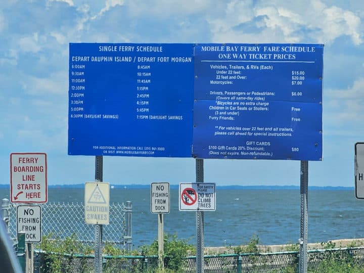 Blue sign with Dauphin Island ferry times and pricing