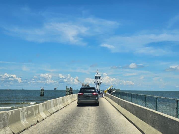 Driving over a bridge with a ferry boat and minivan in front of the car