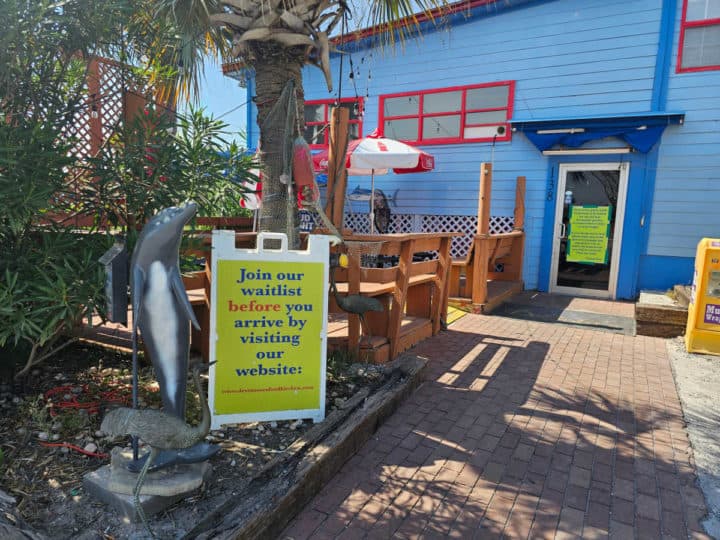 walkway up to a blue building with a waitlist sign and waiting area