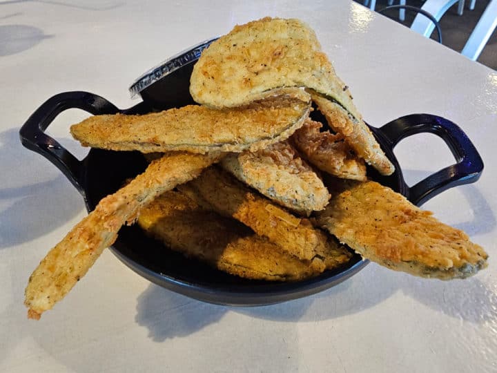 Fried pickle strips in a black container with ranch