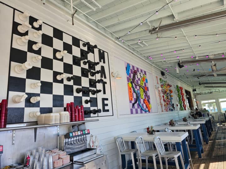 Huge chess set on the wall and funky decorations over tables and chairs