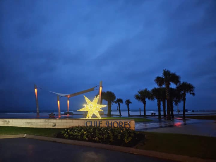 holiday light up star next to Gulf Shores Sign with palm trees and a dark sky