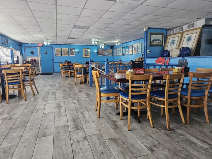 Indoor seating with tables and chairs, blue paint on the walls and shrimp festival art