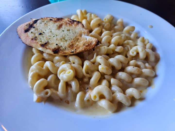 mac and cheese in a white bowl with garlic bread