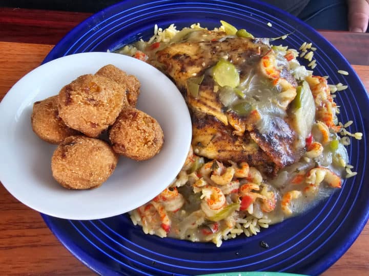 new orleans catch seafood on a blue plate with a side of hushpuppies in a white bowl 
