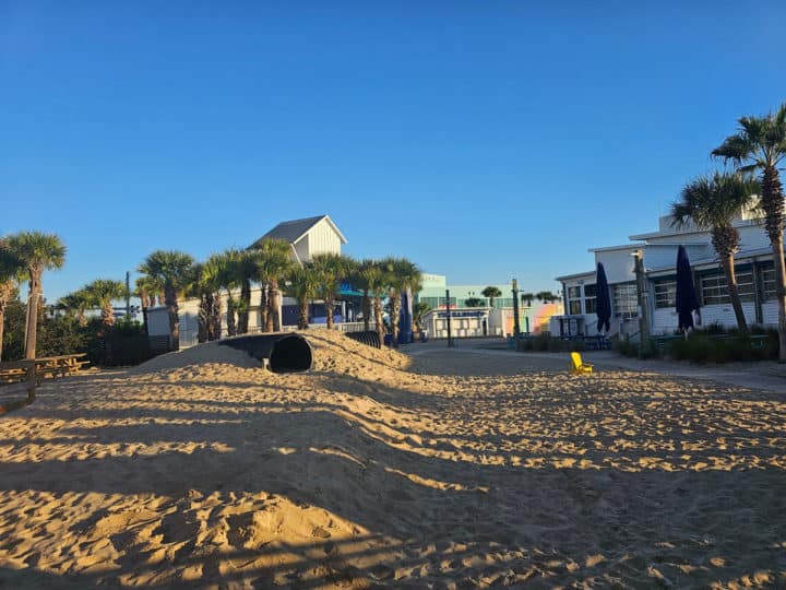 sand pit area with tunnels next to the Hangout building with palm trees in the background