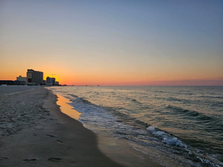 Sunrise over buildings and waves along the shoreline