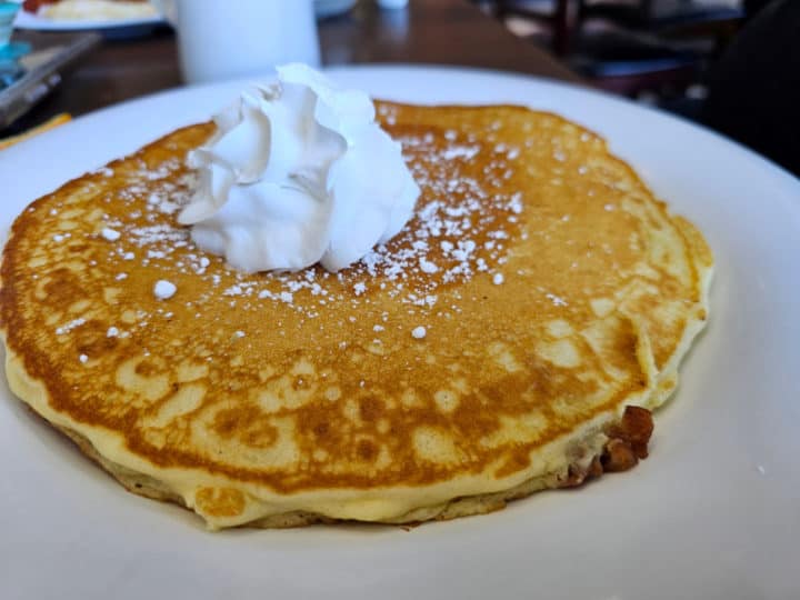 Pancakes with bacon on a white plate, garnished with whipped cream