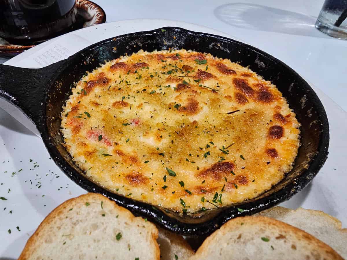 baked pimento cheese dip in a cast iron skillet next to toast slices