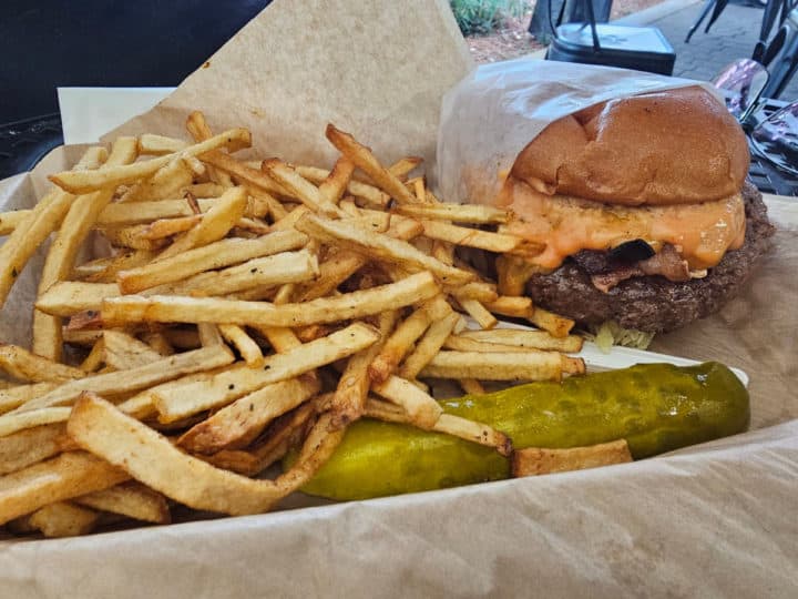 cheeseburger, pickle spear, and skinny fries in a parchment lined basket