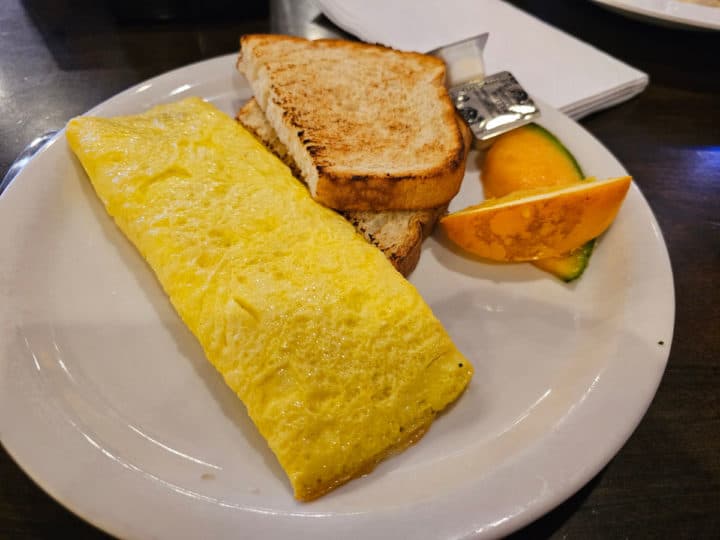 Cheese omelet next to toast and an orange wedge