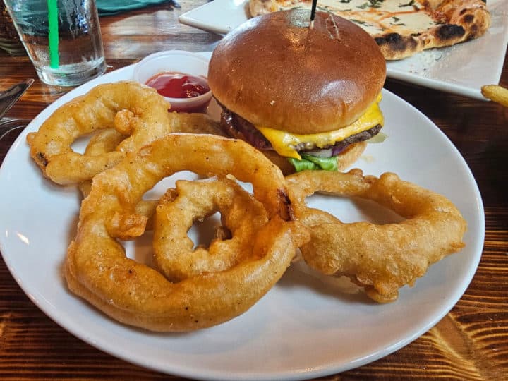 cheeseburger with onion rings on a white plate