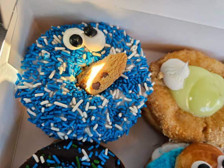 Cookie Monster donut in a bakery box with other donuts