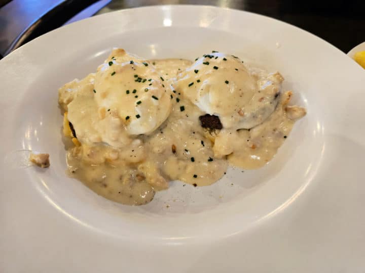 Country benedict with sausage gravy over poached eggs and biscuits