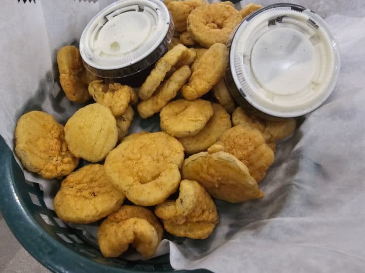 Fried pickles in a basket with containers of ranch dressing