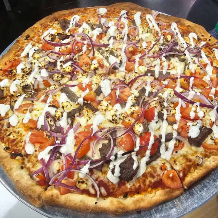 Greek Pizza with sauce, tomatoes, gyro meat, and red onions