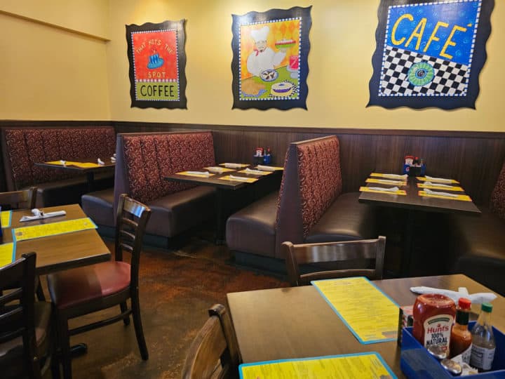 tables and chairs in front of booth seating, yellow walls with coffee art