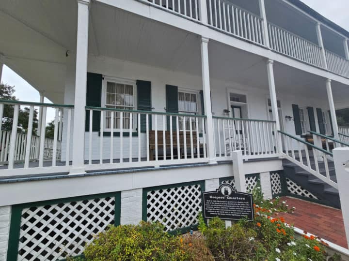 Two story historic white building with Keeper's Quarters sign in front of it. 
