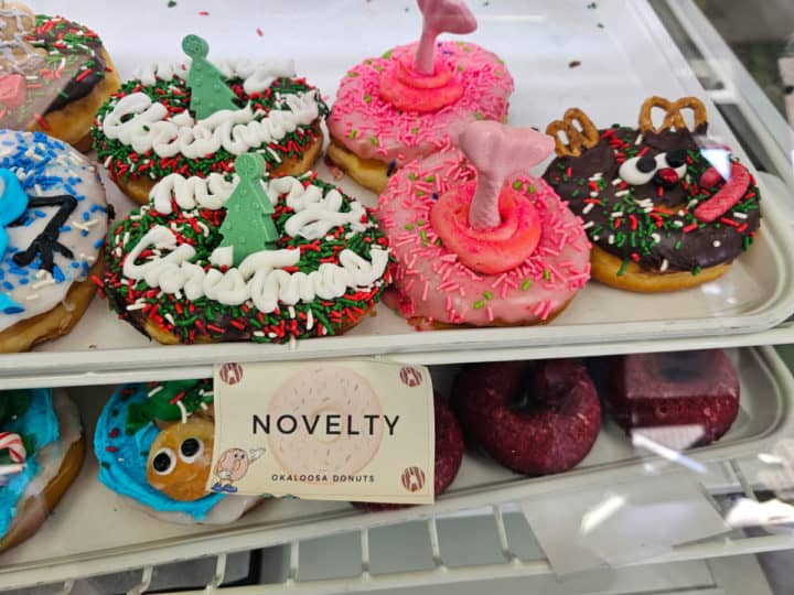 Specialty donuts with merry christmas, a mermaid tail, and reindeer donut on a white tray
