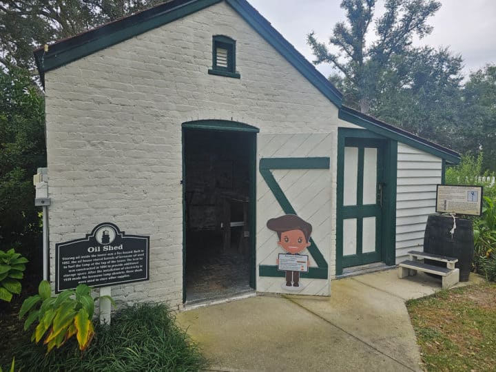 Oil Shed sign next to a white building with the doors open and a cartoon child